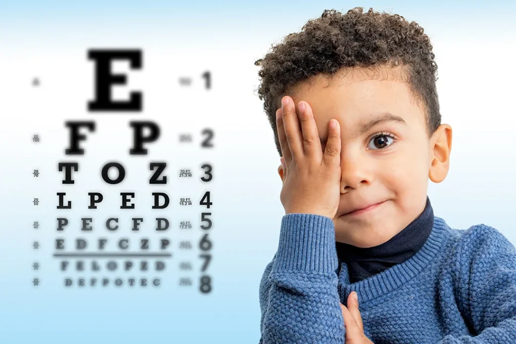 boy covering one eye in front of an eye chart